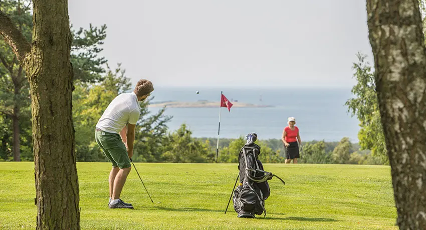 Golfer at Ringenäs golf club with a view of the sea.